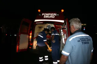 Trei persoane în uniforme de serviciu stau lângă spatele unui vehicul de intervenție deschis, noaptea.
