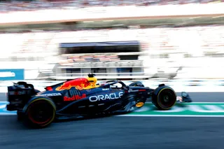 Un monopost de Formula 1 negru cu detalii albastre și roșii circulă pe un circuit de curse.
