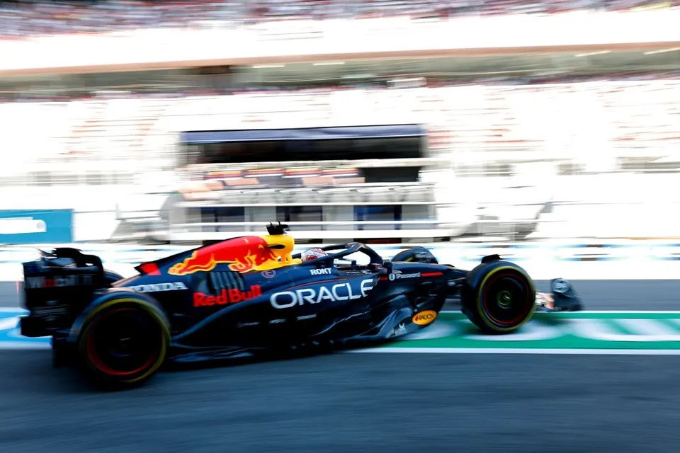Un monopost de Formula 1 negru cu detalii albastre și roșii circulă pe o pistă de curse într-un cadru cu mișcare blurată.