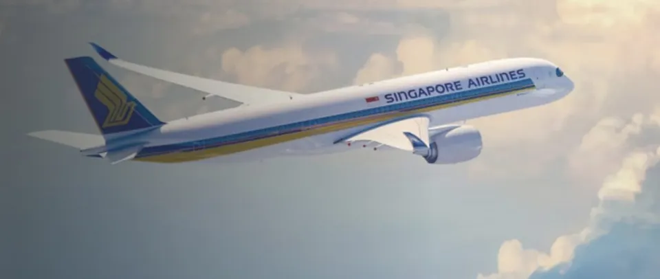 Un avion de pasageri alb cu dungi galbene și albastre zboară prin nori sub un cer luminos.