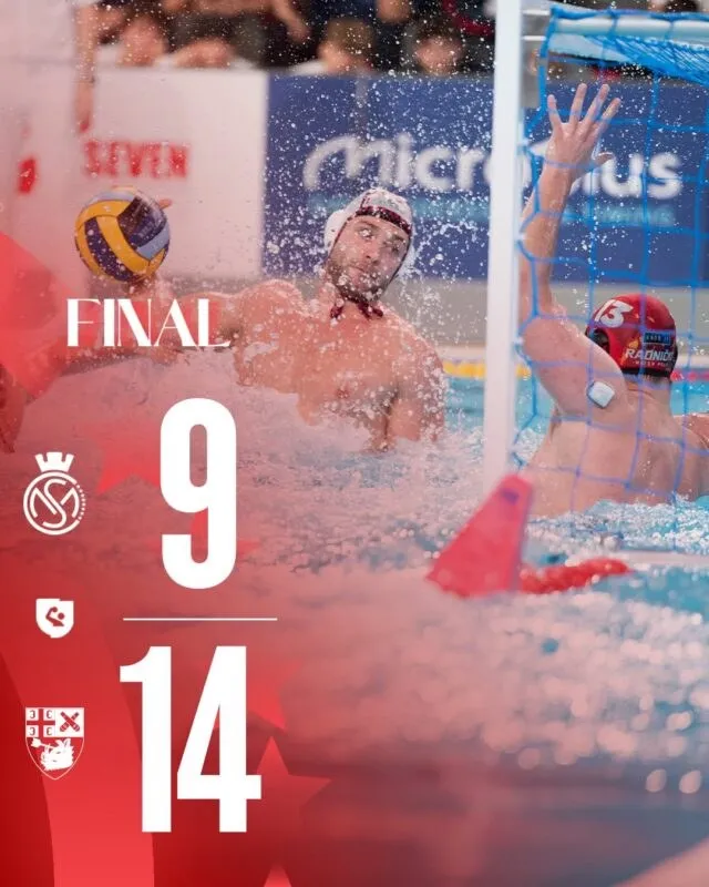 Un jucător de waterpolo cu căciulă albă ridică o minge de waterpolo în timp ce un alt jucător se află în fața unui gol.