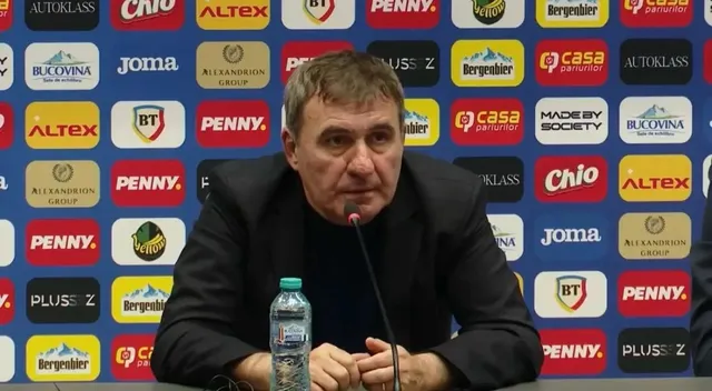 Un bărbat cu părul scurt și cămașă neagră stă la o masă în fața unui panou cu diverse logo-uri colorate.