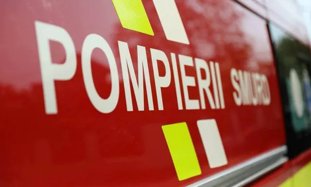 Un detaliu de pe un vehicul roșu prezintă inscripțiile albe POMPIERII și SMURD alături de elemente geometrice galbene și albe.
