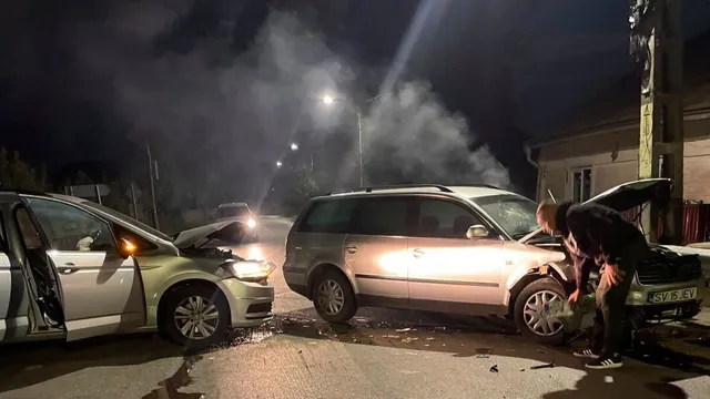 Două autoturisme sunt oprite pe un drum noaptea, în timp ce un bărbat stă în picioare lângă capota deschisă a unui vehicul argintiu.