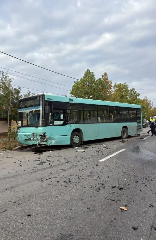 Un autobuz de culoare turcoaz stă pe o stradă cu resturi de materiale împrăștiate pe asfalt în fața sa.