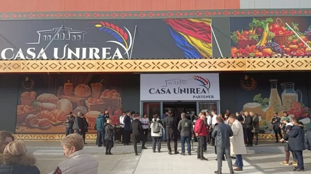 Un grup de persoane stă în fața unei clădiri cu panouri publicitare pe care scrie Casa Unirea.