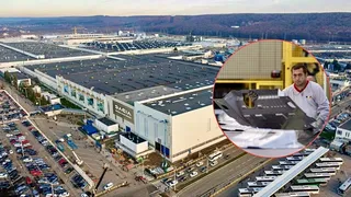 O vedere aeriană a unei fabrici mari cu clădiri industriale și parcări auto, suprapusă cu un cerc ce înfățișează un bărbat în haine de lucru.