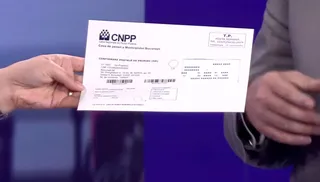 A person holds a white CNPP pension document with printed text and barcodes against a blue background.