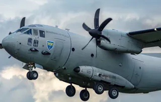 O aeronavă militară gri cu marcajul Romanian Air Force zboară pe un cer înzăpezit.