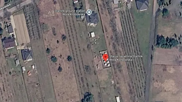 O imagine satelitară arată o zonă rurală cu terenuri, câteva clădiri și un marcaj de locație roșu pe o structură mică.