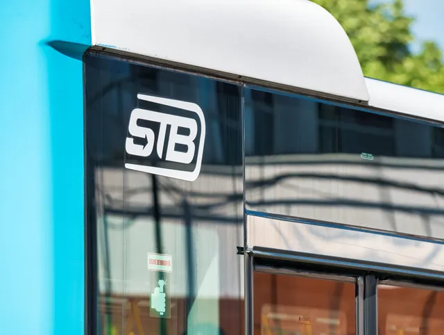 Un detaliu al unui vehicul albastru și alb cu logo-ul STB aplicat pe geamul lateral.