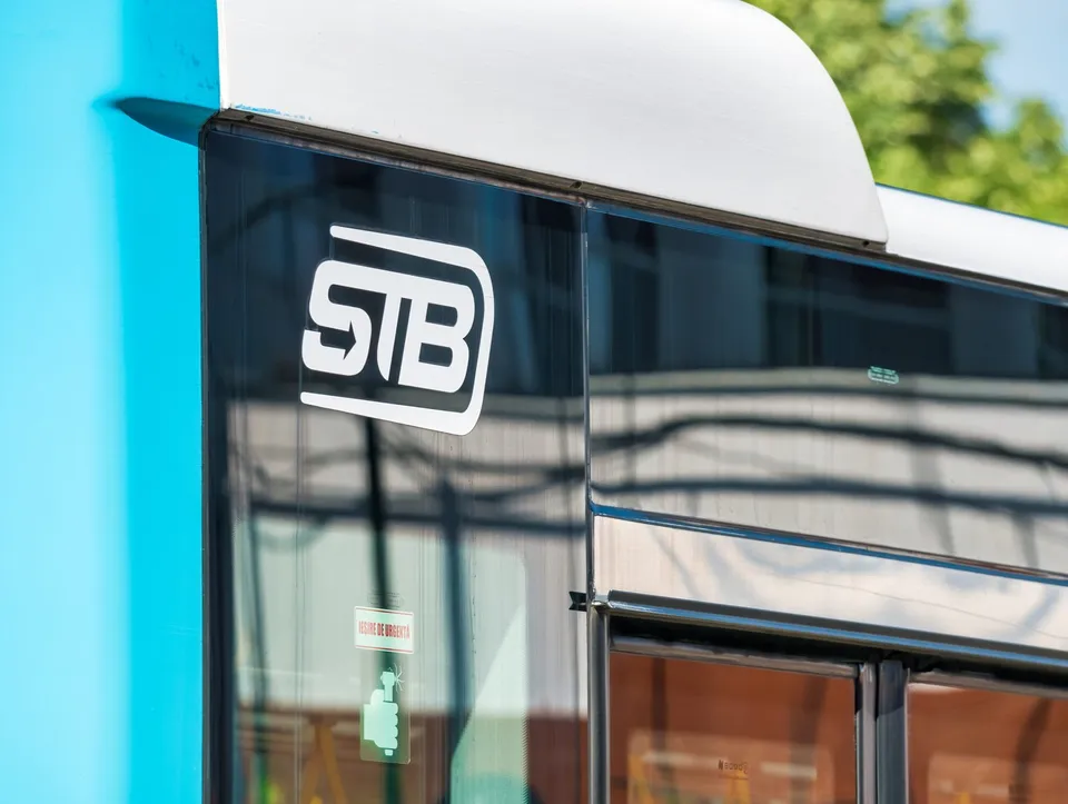 Un detaliu al unui vehicul albastru și alb cu logo-ul STB aplicat pe geamul lateral.