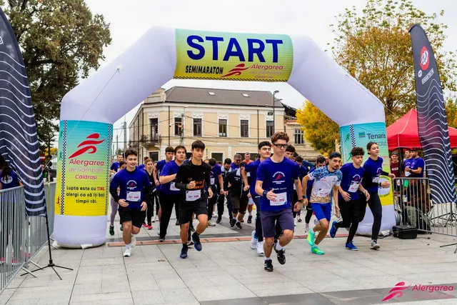 Mulți alergători în echipamente sportive trec pe sub o arcadă gonflabilă albă pe care scrie START.