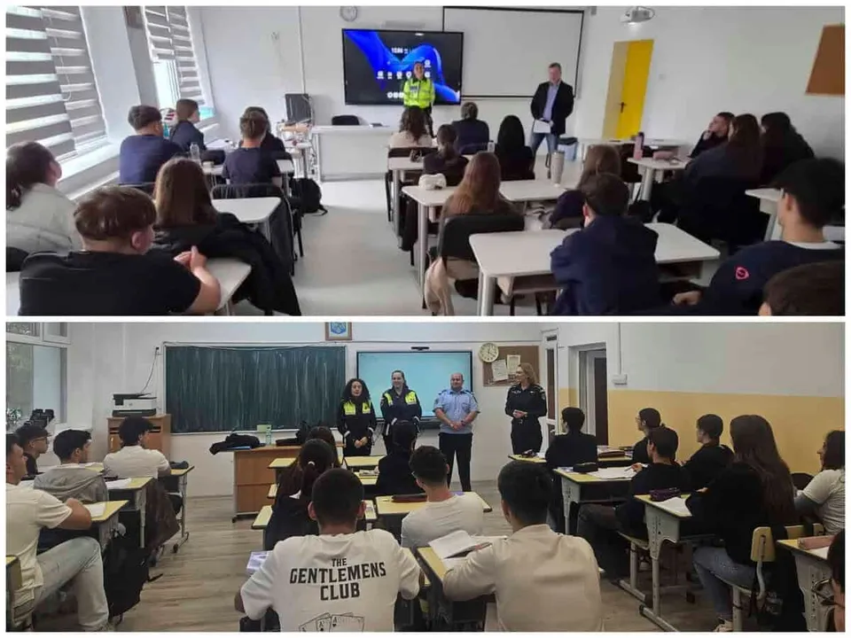 Elevi stau la bănci într-o sală de clasă în timp ce câțiva adulți stau în față lângă un ecran și o tablă.