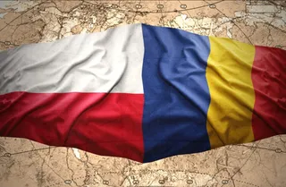 Două steaguri, unul alb cu roșu și unul albastru, galben și roșu, sunt suprapuse pe un fundal de hartă maronie.