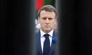 Un bărbat cu părul scurt, purtând o cămașă albă, o cravată neagră și un sacou închis la culoare, privește spre înainte.