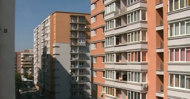 Blocuri de apartamente înalte cu balcoane și ferestre sunt situate sub un cer senin.