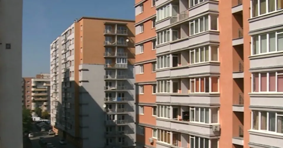Blocuri de apartamente înalte cu balcoane și ferestre sunt situate sub un cer senin.