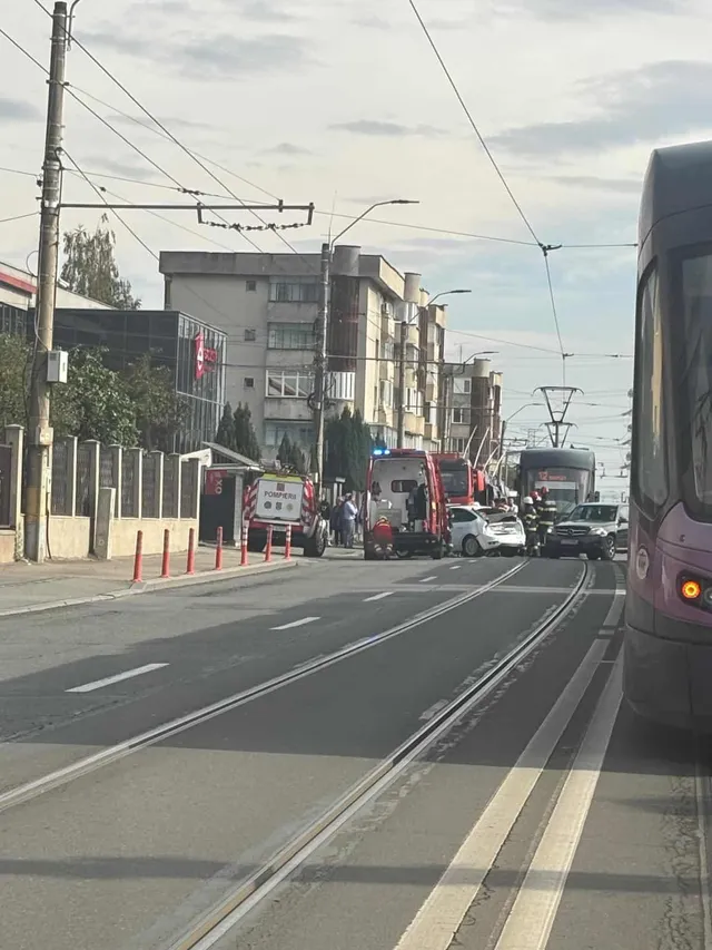 Un tramvai și mai multe vehicule de serviciu de urgență sunt oprite pe o stradă cu șine de tramvai și clădiri în fundal.