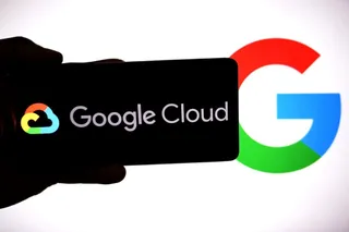 O mână ține un smartphone care afișează logoul și textul Google Cloud pe un fundal negru, lângă un simbol Google de dimensiuni mari.
