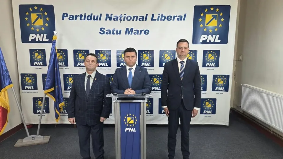 Trei bărbați în costume purtând cravate stau în picioare în fața unui panou alb cu logourile PNL.