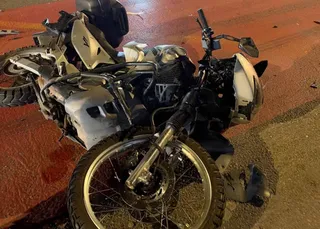 O motocicletă albă și neagră este răsturnată pe asfaltul de culoare închisă.