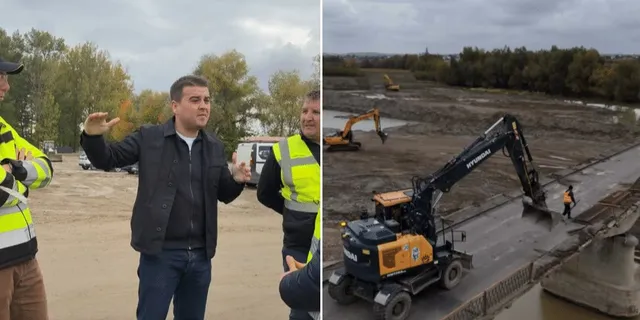 Un bărbat într-o jachetă neagră stă în picioare lângă doi lucrători cu veste reflectorizante, în timp ce o excavatoare lucrează pe o suprafață de beton.