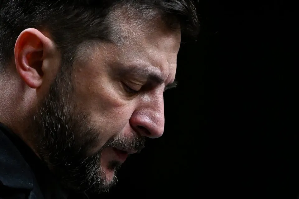 Un bărbat cu barbă și păr scurt este surprins într-o poză de profil, cu ochii închiși, pe un fundal negru.