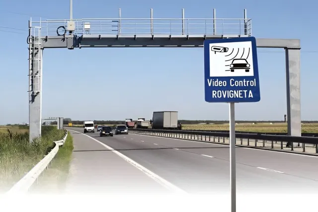 O structură metalică de tip portal traversează o autostradă pe unde circulă câteva vehicule sub un cer senin.
