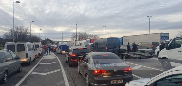 Mai multe vehicule de transport, inclusiv autoturisme și furgonete, sunt implicate într-un rând de trafic pe o autostradă sub un cer înnorat.