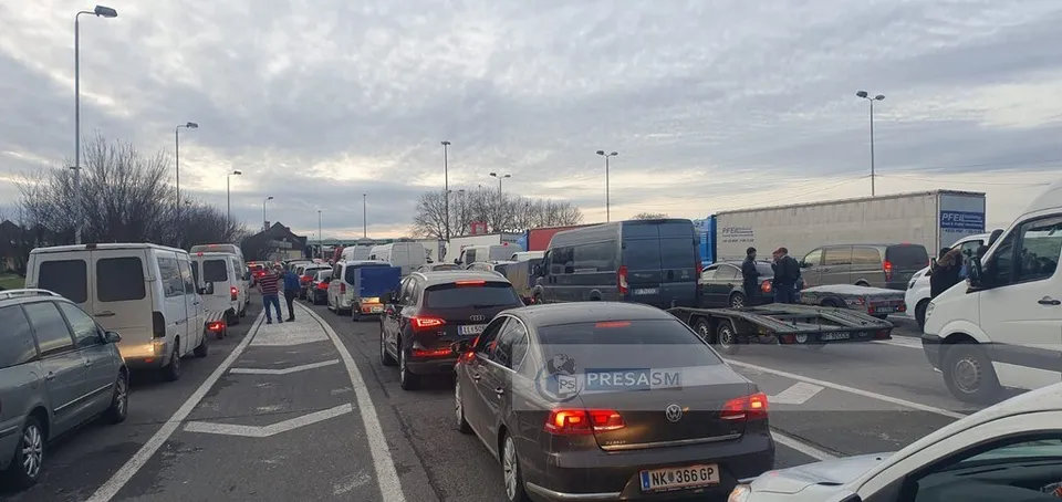Mai multe vehicule de transport, inclusiv autoturisme și furgonete, sunt implicate într-un rând de trafic pe o autostradă sub un cer înnorat.