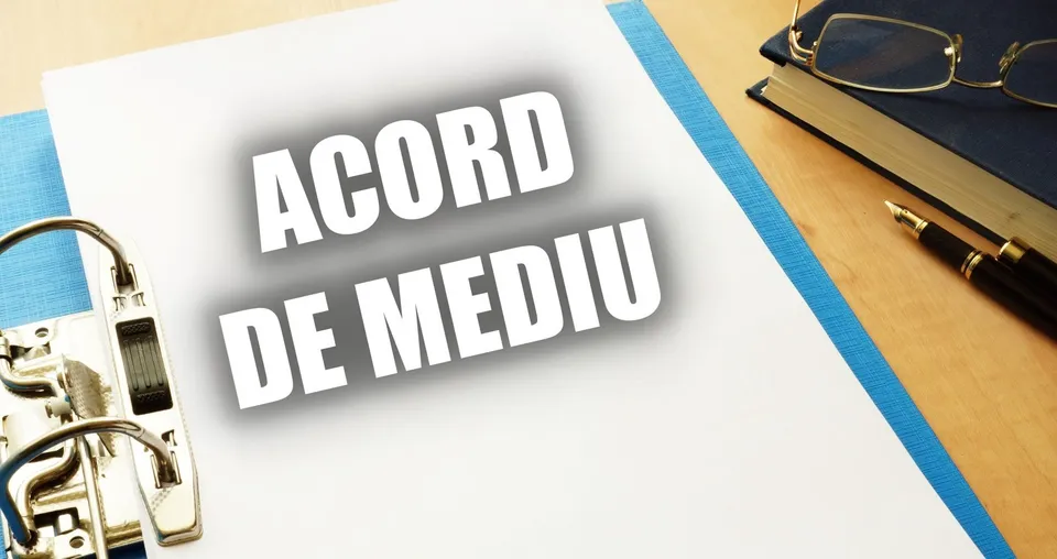Un dosar cu textul ACORD DE MEDIU este așezat pe o masă lângă ochelari, un stilou și o carte.