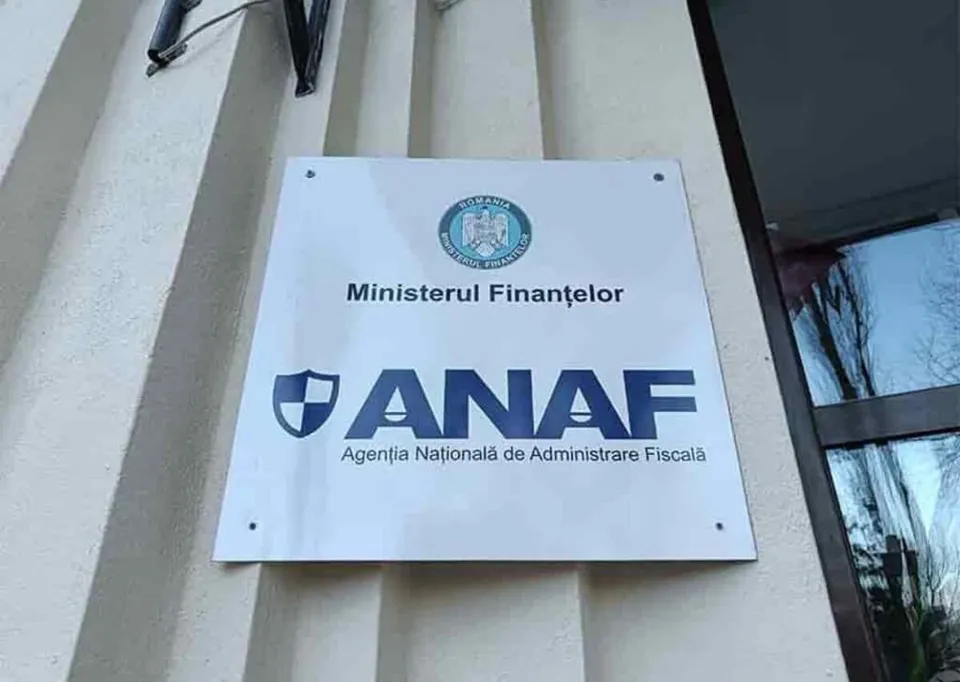 Un panou alb cu siglul Ministerului Finanțelor și textul ANAF este montat pe o fațadă de clădire cu strii verticale.