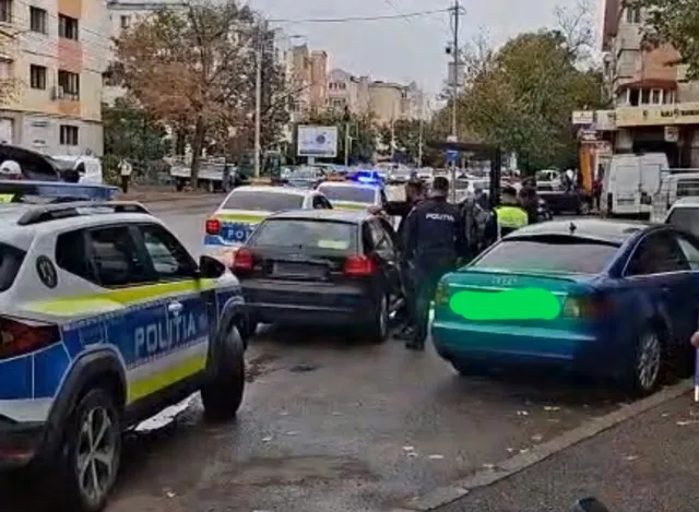 Mai multe mașini sunt oprite pe un drum urban lângă un vehicul de poliție albastru și alb cu inscripția POLITIA.