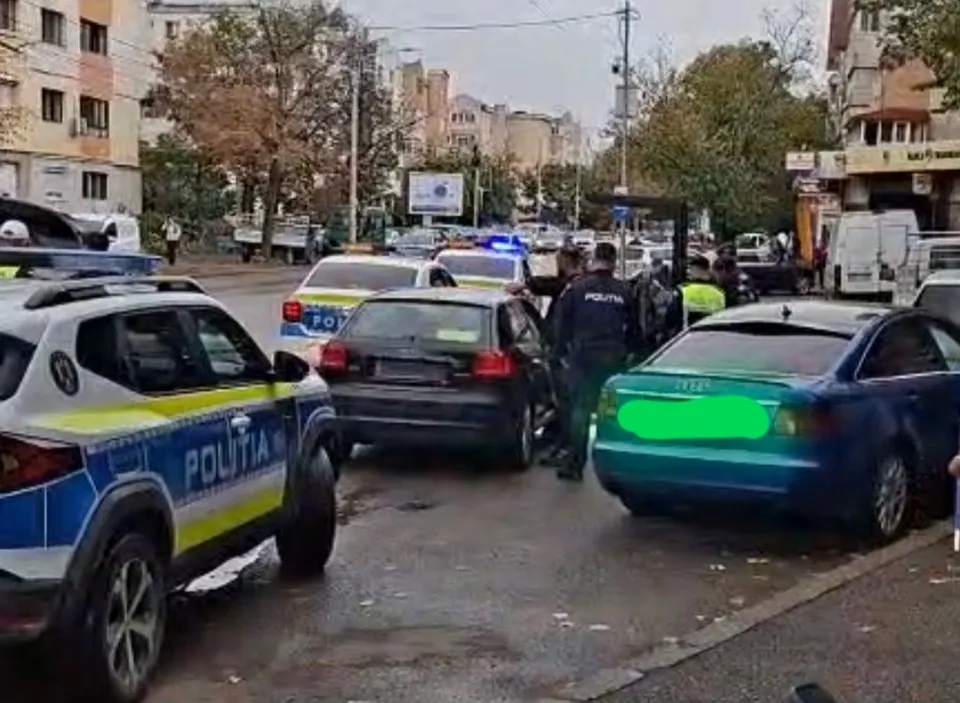 Mai multe mașini sunt oprite pe un drum urban lângă un vehicul de poliție albastru și alb cu inscripția POLITIA.