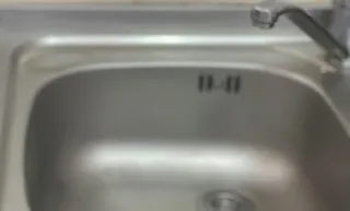 O chiuvetă metalică de bucătărie cu un robinet montat în partea dreaptă sus.