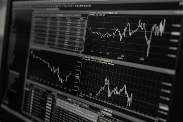 Un ecran de computer afișează mai multe grafice de tip linie și tabele de date financiare pe un fundal întunecat.