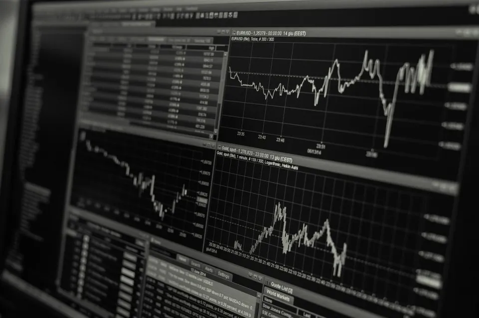 Un ecran de computer afișează mai multe grafice de tip linie și tabele de date financiare pe un fundal întunecat.