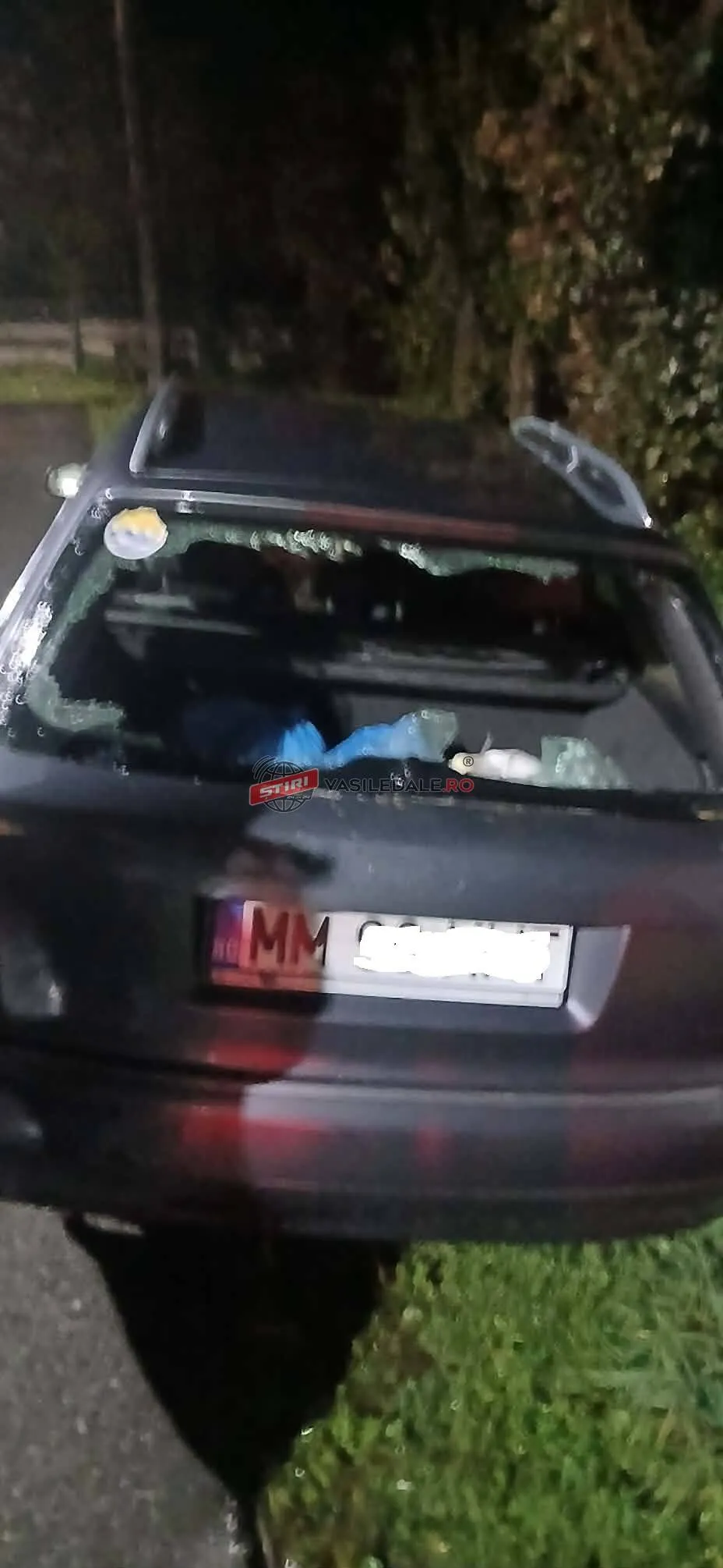 Un autoturism negru prezintă luneta spartă și resturi de sticlă pe pervazul posterului.