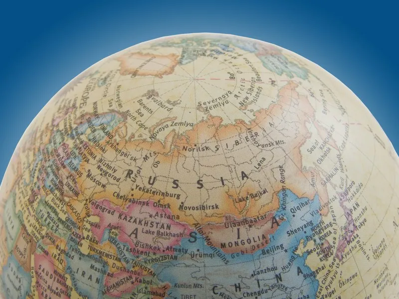 Prim-plan cu un glob terestru colorat, pe care apar Europa de Est, Rusia și Asia Centrală, pe un fundal albastru.