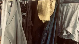 Haine de diverse culori și materiale sunt agățate pe un suport de uscat în interiorul unei încăperi.