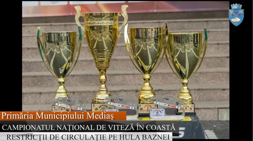 Patru trofee aurii sunt așezate pe un suport pe trepte de piatră.
