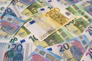Mai multe bancnote de euro de diferite valori sunt împrăștiate pe o suprafață plană.