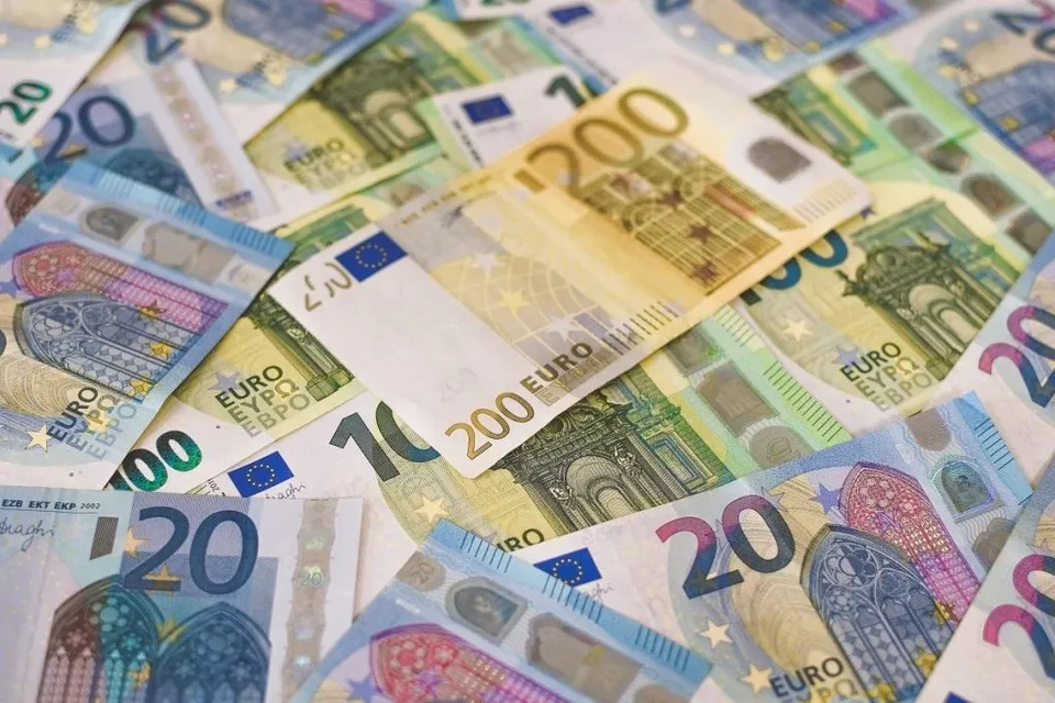 Mai multe bancnote de euro de diferite valori sunt împrăștiate pe o suprafață plană.
