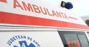Partea superioară a unei ambulanțe albe cu textul roșu AMBULANȚA și o lumină albastră pe acoperiș.