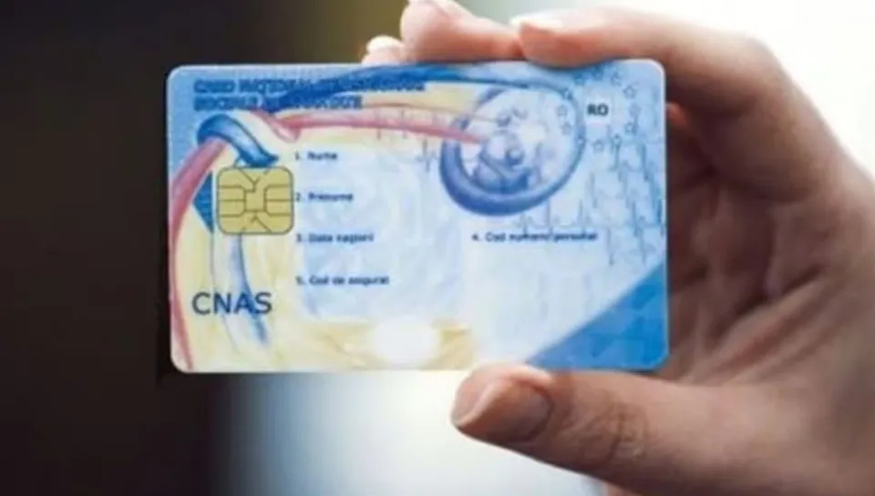 O mână ține un card dreptunghiular albastru cu text și un cip metalic pe o suprafață neclară.