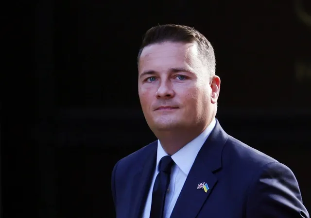 Un bărbat cu părul scurt, îmbrăcat în costum închis la culoare, cămașă albă și cravată neagră, poartă un pin cu steagul Ucrainei pe reverul sacoului.