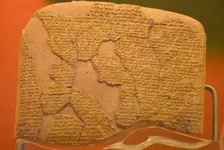 Un fragment de tăbliță de lut de culoare maro deschis prezintă inscripții cu caractere mici pe întreaga sa suprafață texturată.