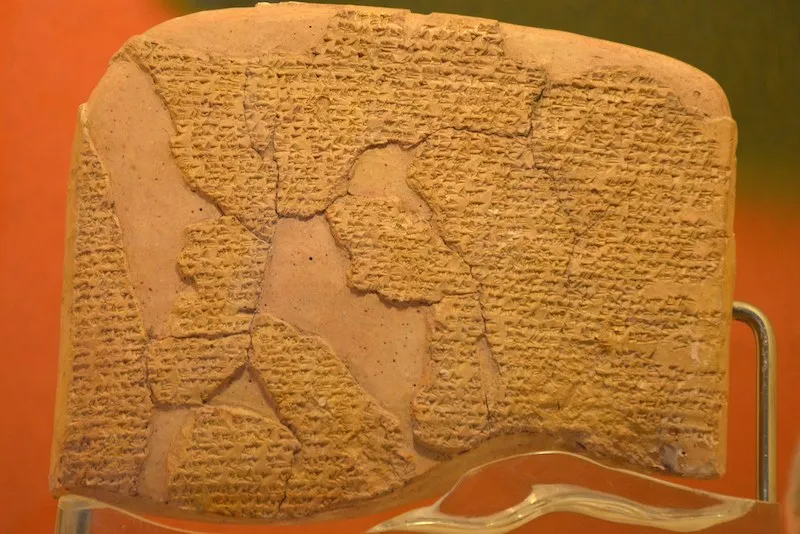 Un fragment de tăbliță de lut de culoare maro deschis prezintă inscripții cu caractere mici pe întreaga sa suprafață texturată.