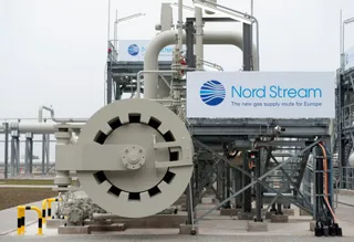 O instalație industrială cu conducte gri, valve mari și un panou alb cu textul Nord Stream este situată sub un cer încorporat.